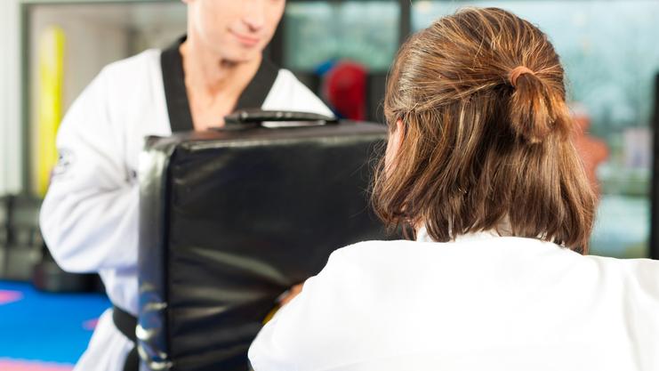 Ein Taekwondo-Praktizierender schlägt gegen einen gepolsterten Trainingsblock in einem Sportstudio.